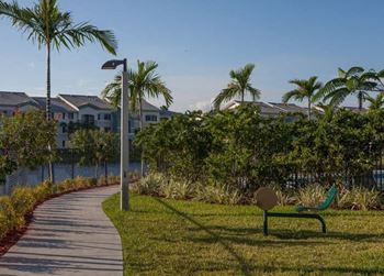 a pathway through a park with palm trees and houses
